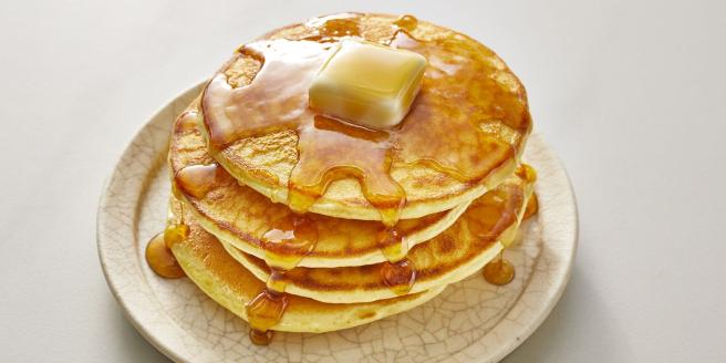 A stack of pancakes topped with syrup and butter.