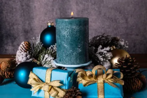 A blue candle atop a pile of presents in blue wrapping paper